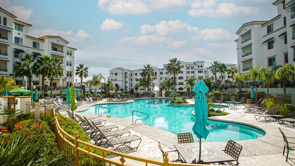 This image showcases a sparkling swimming pool surrounded by sun loungers and palm trees, with water features adding a touch of luxury. The inviting atmosphere emphasizes relaxation and social gatherings, with spaces for both sunbathing and connecting with others poolside.