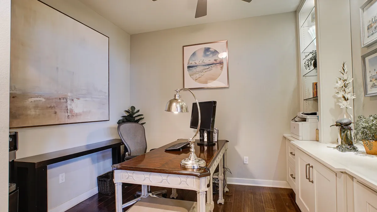 A dedicated office nook within a comfortable interior, showcasing a modern desk, ergonomic office chair, wall art, and a lamp—creating a productive and inviting workspace.