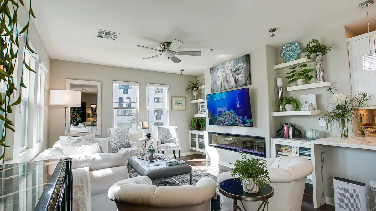 This calm and serene living area features a large television (with an aquarium display), comfortable seating, a coffee table with decorative items, and green plants. The arrangement is ideal for movie nights or casual gatherings, echoing the section's focus on relaxation and entertainment.