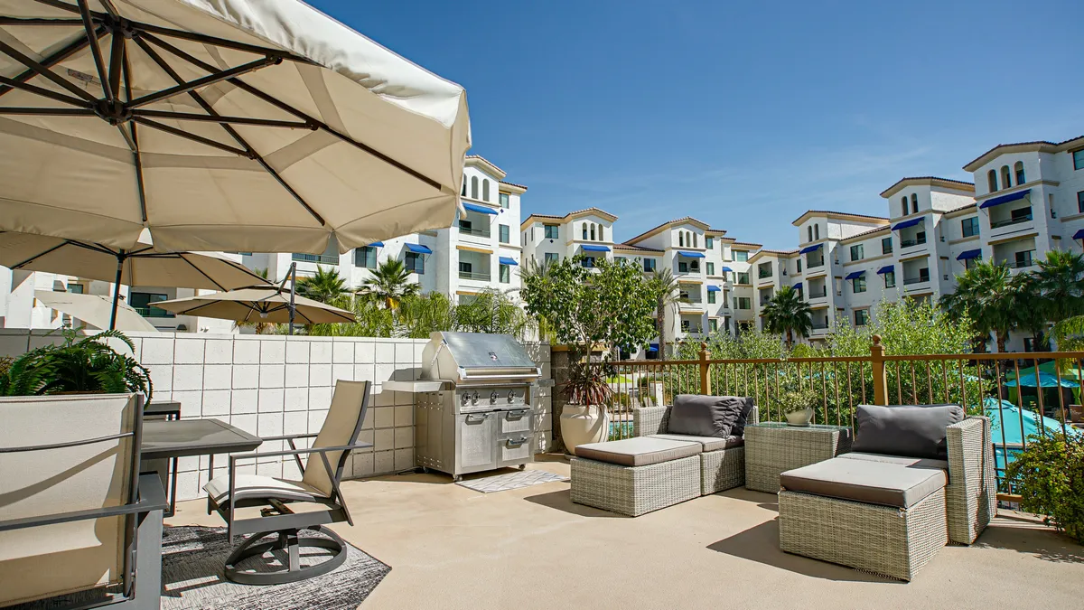 An inviting outdoor seating area with a barbecue grill, potted plants, and a swimming pool in the background. The space exudes relaxation and leisure, perfect for unwinding after a day of golf or socializing with friends.
